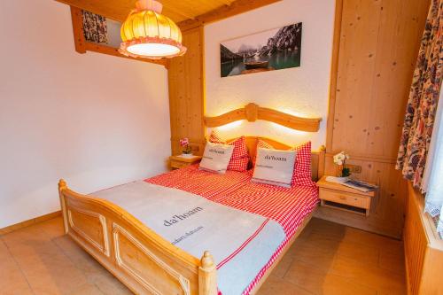 a bedroom with a wooden bed with red and white pillows at Bergidyll 3 by Alpenidyll Apartments in Ramsau am Dachstein