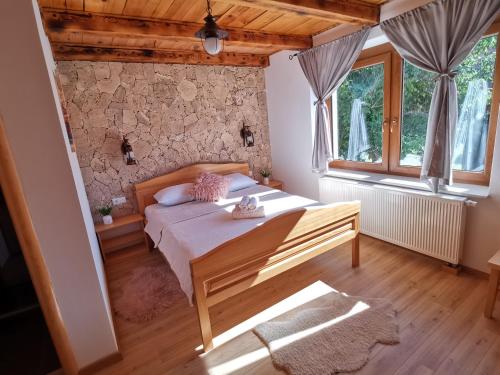 a bedroom with a bed and a stone wall at Plitvice Antico in Gornji Babin Potok