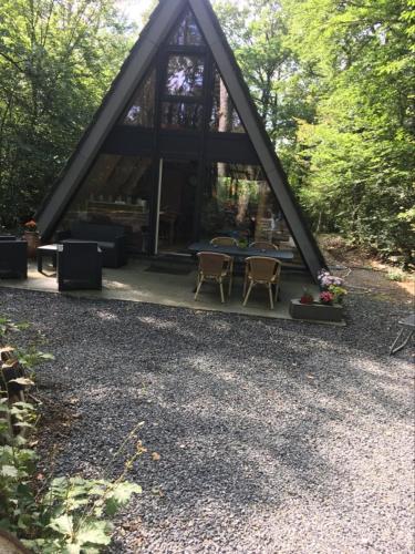 a cabin with a table and chairs in the woods at La Bulle Du Trappeur (Chevaux bienvenus) in Pondrôme