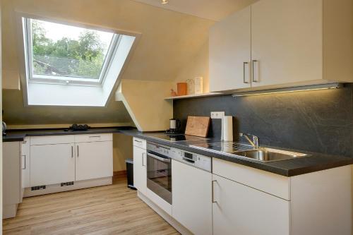 una pequeña cocina con fregadero y ventana en Panorama-Fewo Töpfer, en Annweiler am Trifels