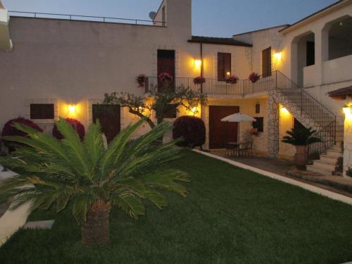 a house with a palm tree in the yard at night at Le Zarafe in Caltabellotta