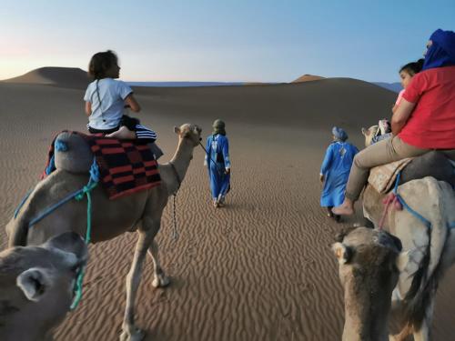 een groep mensen die op kamelen rijden in de woestijn bij Bivouac Erg Chegaga Nomademoi in El Gouera