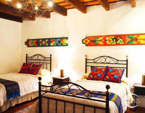 a bedroom with two beds with colorful pillows at Luna Maya Antigua in Antigua Guatemala