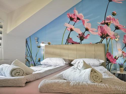 - une chambre avec 2 lits et des fleurs sur le mur dans l'établissement Apartman Ananas Banja Luka centar bolnica besplatan parking, à Banja Luka