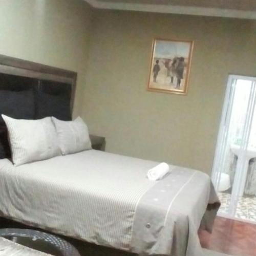 a bedroom with a white bed and a window at Authentic Bicycle Tours and Backpackers in Soweto