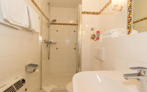 een witte badkamer met een douche en een wastafel bij Quisisana10 in Sankt Peter-Ording