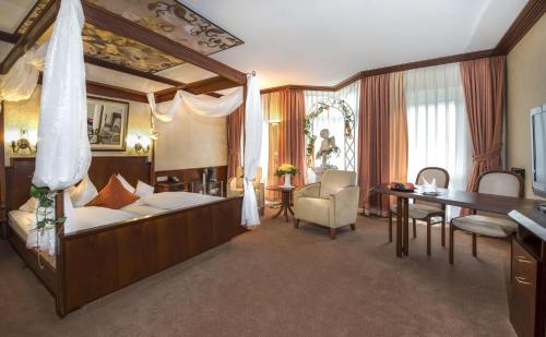 Parkhotel Stadtallendorf في شتاتالندورف: غرفة نوم مع سرير مظلة مع مكتب وطاولة