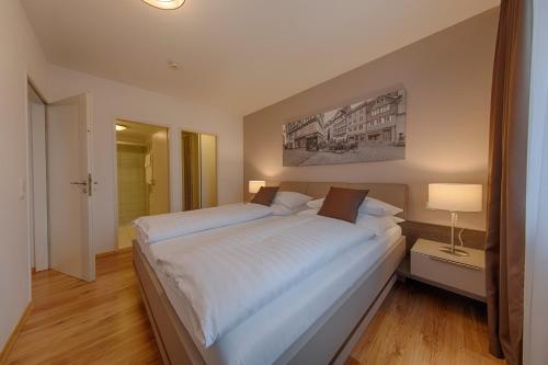ein Schlafzimmer mit einem großen weißen Bett und einer Lampe in der Unterkunft Appartement 41 Executive mit Flußblick in Wetzlar