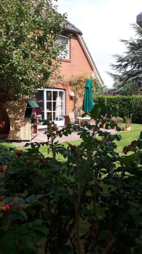a house with a garden with a patio and an umbrella at Apfelgarten in Boldixum