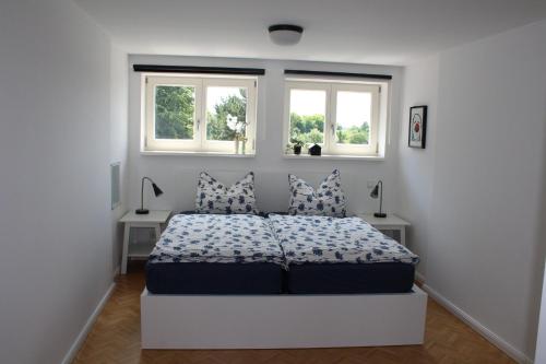 a white bedroom with a bed and two windows at Turmfalke in Bad Sülze