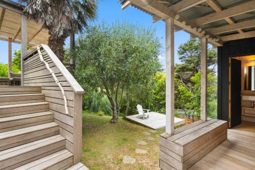 a house with a wooden staircase and a patio at Palm Views - Stay Waiheke in Palm Beach