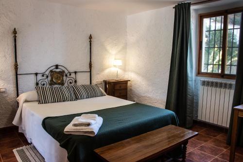 Schlafzimmer mit einem Bett, einem Tisch und einem Fenster in der Unterkunft Cauchil Chico in Alcalá la Real