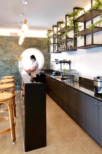 a kitchen with a person standing at a counter at Beds & Friends Hostel Mactan with Pool and Bar in Mactan