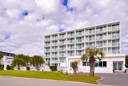 a white building with palm trees in front of it at Cabana Shores Hotel in Myrtle Beach