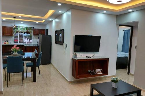 a living room with a table and a television on a wall at Cómodo Apto de 2hab con Aire 2baños, cerca de todo en Alma Rosa I in El Seis