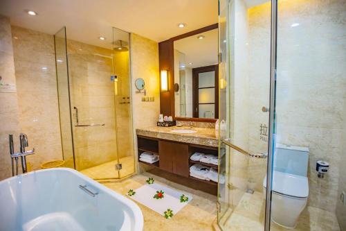 a bathroom with a tub and a shower and a sink at Ocean View Resort Yalong Bay in Sanya