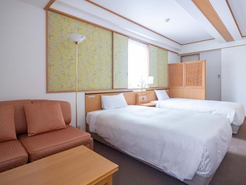 長崎市にあるホテルクオーレ長崎駅前のベッド2台とソファが備わるホテルルームです。