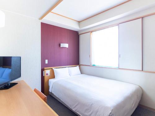 a hotel room with a bed and a tv at Hotel Cuore Nagasaki Ekimae in Nagasaki