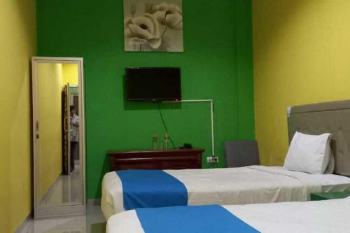 een slaapkamer met 2 bedden en een groene muur bij RedDoorz near Bandara Adi Soemarmo Solo in Tjolomadu