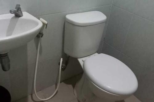 a bathroom with a white toilet and a sink at RedDoorz near Bandara Adi Soemarmo Solo in Tjolomadu