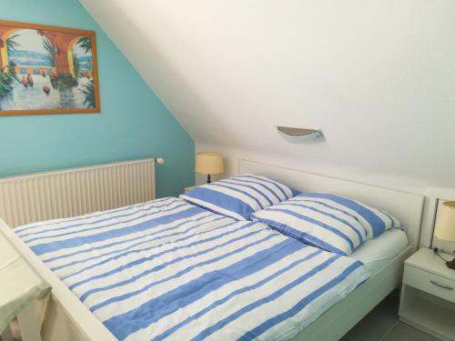 a bed with two blue and white striped pillows at Ferienwohnung Schmetterling II in Großenbrode
