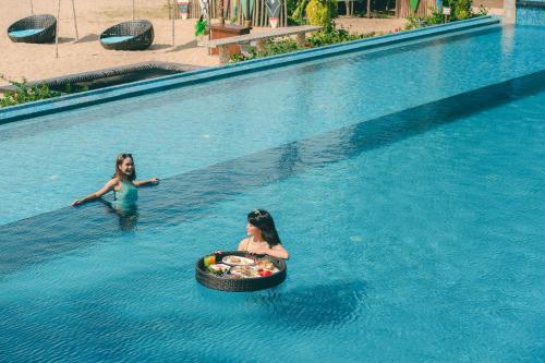 two girls in a swimming pool with a ball in the water at Dhevan Dara Beach Villa Kuiburi in Kui Buri