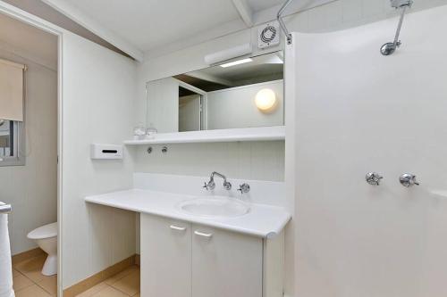 a white bathroom with a sink and a mirror at The Bay Beach Studio ~ Ocean View in Apollo Bay