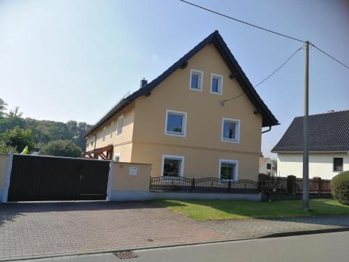 a large yellow house with a black fence at Pension Schlossblick Thallwitz in Thallwitz