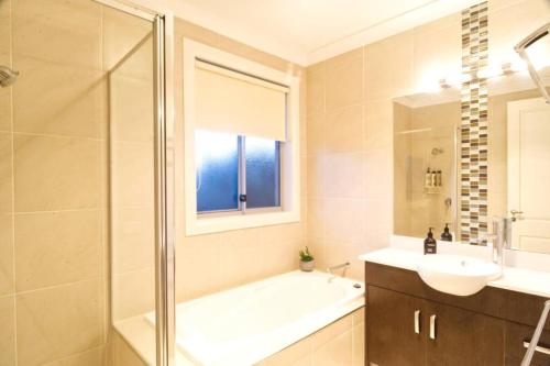 a bathroom with a tub and a sink and a shower at Beachside Bliss with Secure yard l Pet Friendly in Apollo Bay