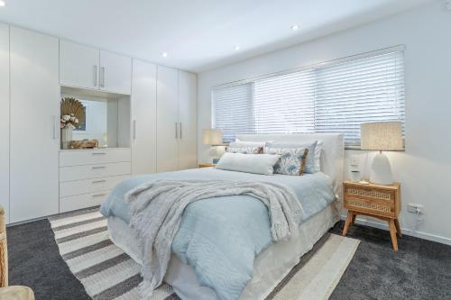 a white bedroom with a bed and a window at Luxe coastal village home, Peregian Beach in Peregian Beach