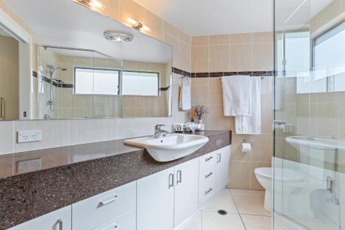 a bathroom with a sink and a toilet and a shower at Luxe coastal village home, Peregian Beach in Peregian Beach