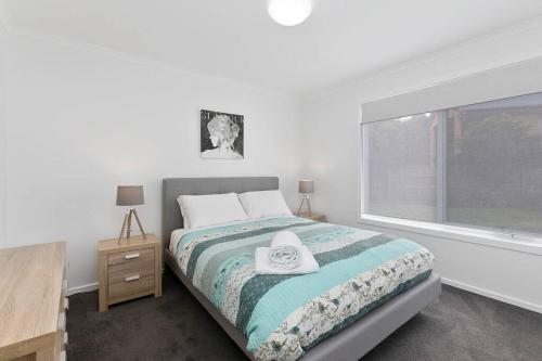 a white bedroom with a bed and a window at Charlie’s Beach House 1Block to Beach Pet Friendly in Apollo Bay