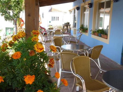 un patio extérieur avec des tables, des chaises et des fleurs orange dans l'établissement Posada la Maza, à Arnuero