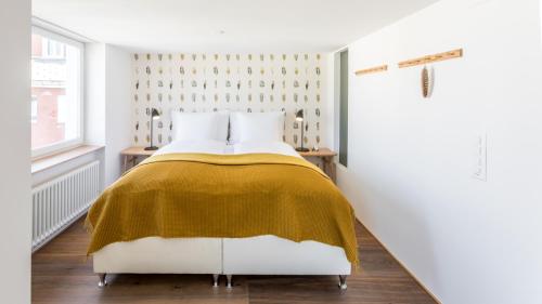 a bedroom with a bed with a yellow blanket at Boutique Hotel St. Georg in Einsiedeln