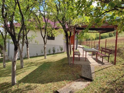 a picnic table and benches in a park with trees at Villa Ramea in Kovačevo Polje