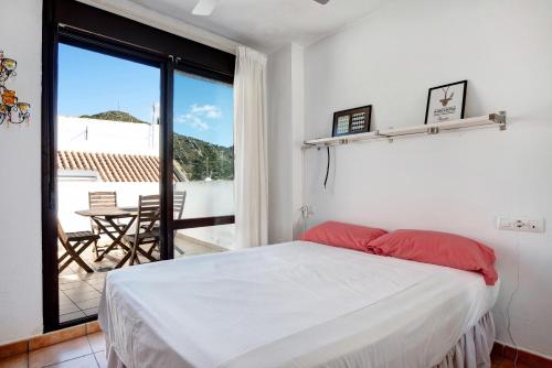 a bedroom with a bed and a balcony with a table at Ático Heaven in Earth in Zahara in Zahara de los Atunes