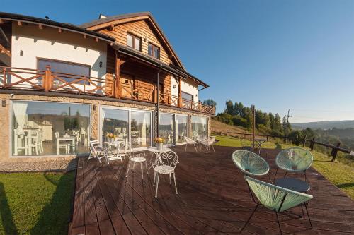 a wooden deck with chairs and a house at Chata w Bieszczadzie widokowe apartamenty w Bieszczadach in Polańczyk