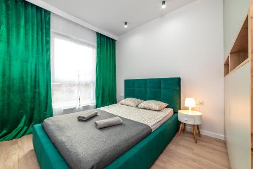 Un dormitorio con una cama grande con cabecero verde. en Apartamenty Przy IV Śluzie - Green, en Bydgoszcz