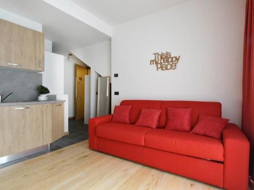 a red couch in a living room with a kitchen at Gressoney Saint-Jean apartments by Halldis in Gressoney-Saint-Jean