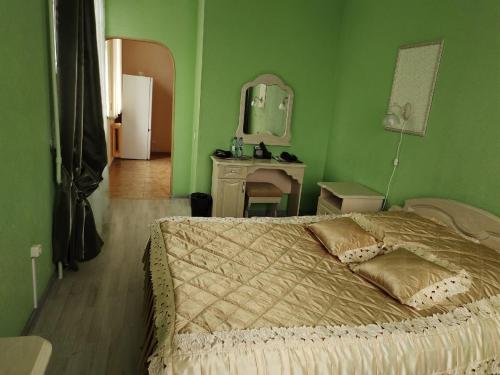 - une chambre verte avec un lit et un miroir dans l'établissement Oktyabrskaya Hotel, à Tver