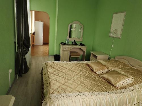 a green bedroom with a bed and a mirror at Oktyabrskaya Hotel in Tver