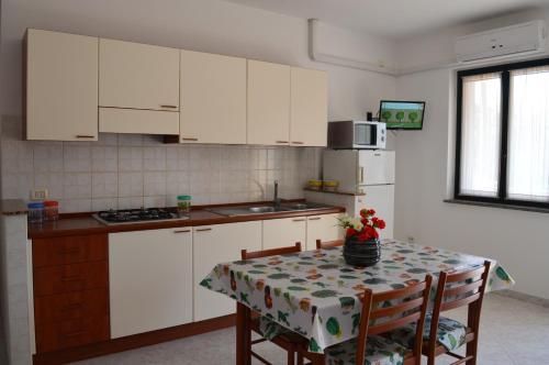 a kitchen with white cabinets and a table with a table cloth at Le Zagare Case Vacanza in Cropani