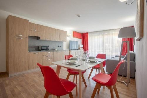 a kitchen and dining room with a table and red chairs at Gressoney Saint-Jean apartments by Halldis in Gressoney-Saint-Jean