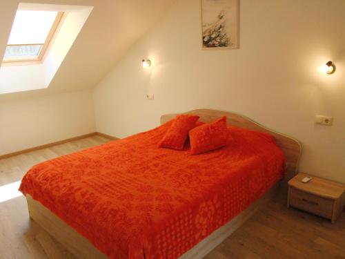 a bedroom with a bed with orange sheets and a window at Irinos Apartamentai in Nida