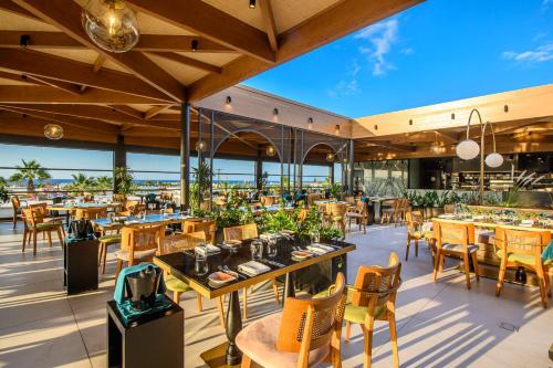 a restaurant with tables and chairs and a view of the ocean at Stella Palace Aqua Park Resort in Hersonissos