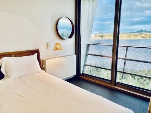 a bedroom with a bed and a large window at Nishi Holiday Apartments in Canberra
