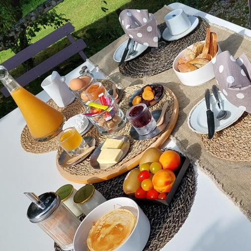 a table with a tray of food and fruit on it at La Loge du Grand Cèdre, chambre d'hôtes SoCosy in Fontcouverte