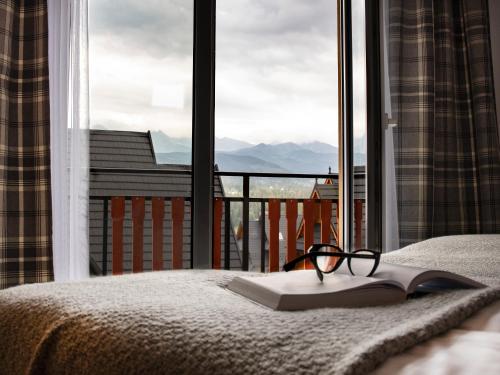 książka i okulary siedzące na łóżku przed oknem w obiekcie Tatrzańskie Spanie pokoje gościnne w Poroninie