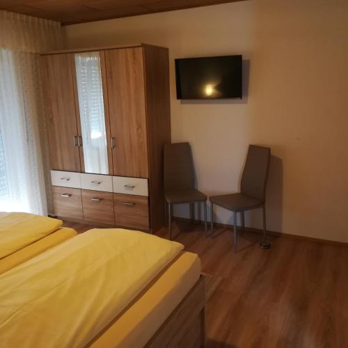 a bedroom with two beds and a desk and a tv at Landhaus Irma in Bad Füssing