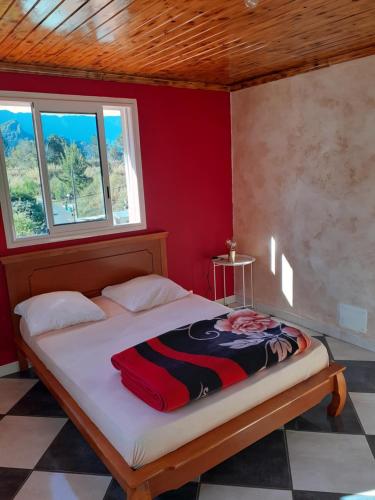 シラオスにあるLa perle des montagnesの赤い壁のドミトリールームのベッド1台分です。